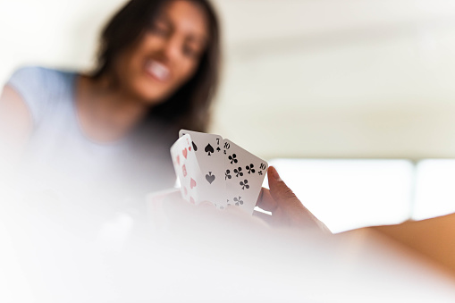 Close up of unrecognizable man playing cards with his girlfriend at home. Copy space.