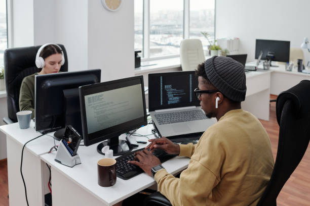istock Contemporary intercultural programmers sitting in front of computers in office 1393771185
