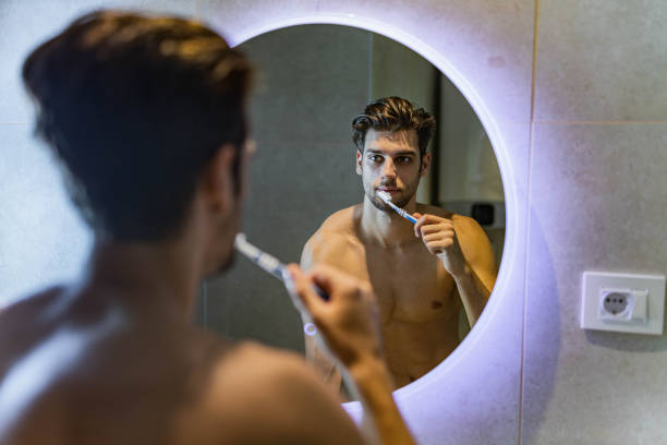istock Reflection in a mirror of a man brushing his teeth in the morning. 1393772200