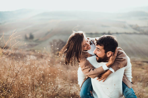 istock Young cheerful couple having fun while piggybacking on a hill. 1393772378
