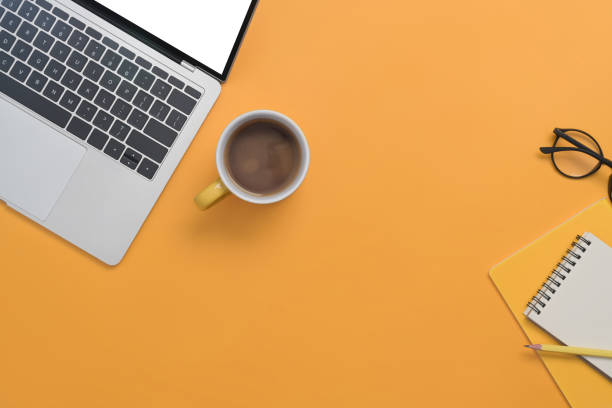 istock Computer laptop, coffee cup and notebook on yellow background with copy space for your text. 1393772517