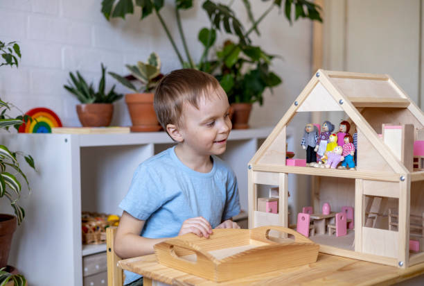 istock Montessori material. Toddler while playing with big pink dollhouse and having a great time. 1393775558
