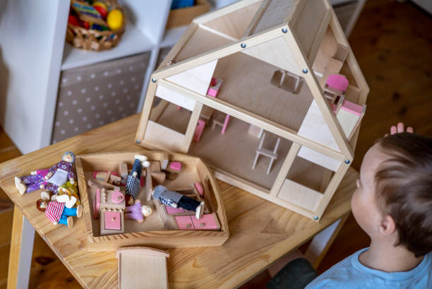 istock Montessori material. Toddler while playing with big pink dollhouse and having a great time. 1393775659