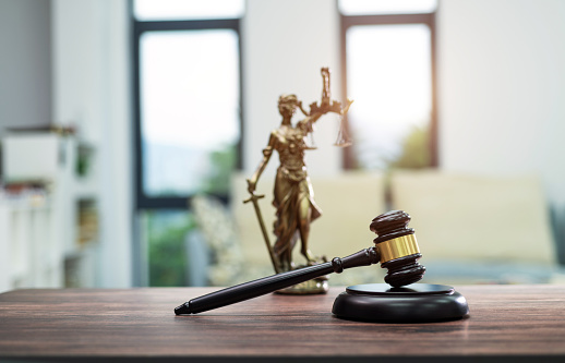 Gavel and lady justice on wooden table.
