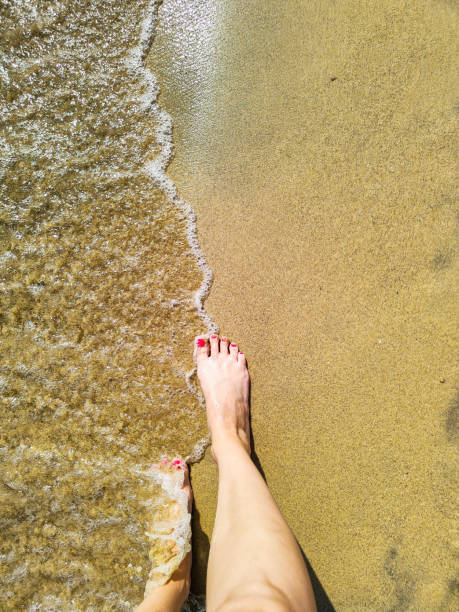 istock Female feet step on the sea wave 1393776902