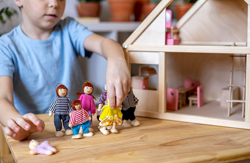 Indoor image of small Kid Boy Playing with wooden tower blocks and demolishing them while playing at home. Boy Building With Wooden Toy Blocks Knocks Over His Tower .