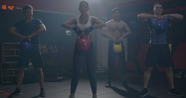 istock Muscular group in exercise gear standing in a row holding dumbbells during an exercise class 1393777945