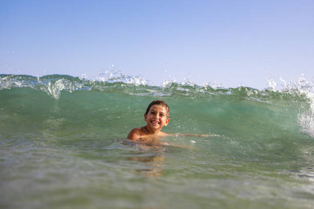 istock Funny kid playing with waves on the beach 1393778730