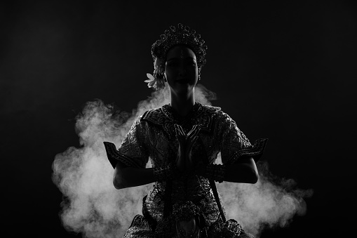 Half body of Asian Woman wear Thai Traditional Costume Dancer, dress silhouette shadow. Khon dance is Act Play Royal of Thailand over black background smoke