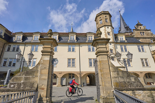 woman on electric bicycle tour on the Route of Castles  in downtown of Öhringen, with its famous Renaissance Residence castle, Baden-Wuerttemberg, Germany