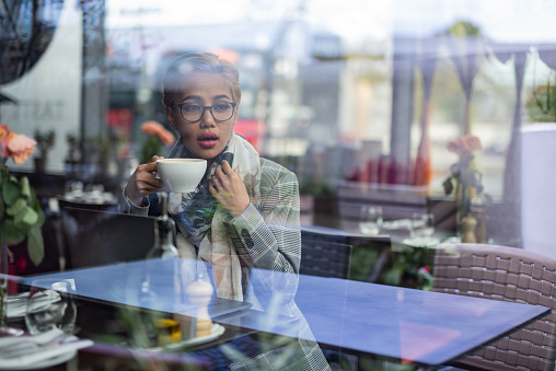 View through the window of a young woman sitting in coffee shop