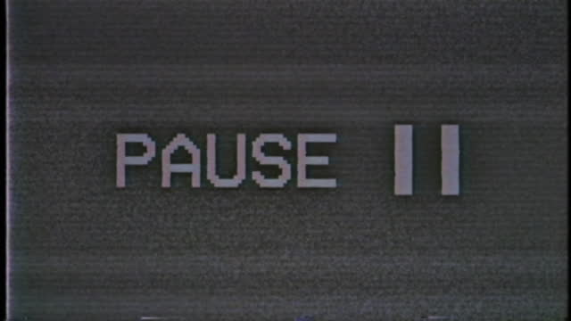 Old damaged VHS tape playing with PAUSE text message on screen