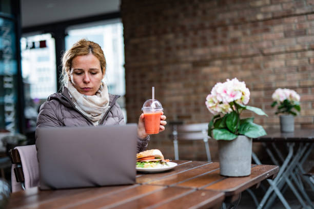Woman in warm clothing have lunch break in cafeteria stock photo