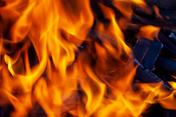 a fire made of logs with a bright flame at a camping while cooking, a flame of fire from the yard, a photo with a small depth of field