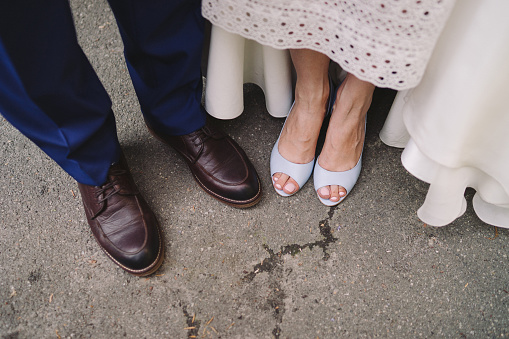 Wedding fashion details. Blue leather shoes on the bride, brown shoes on the groom.