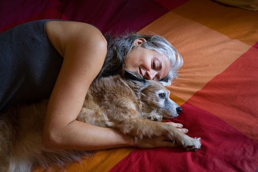 woman lying next to her dog in bed