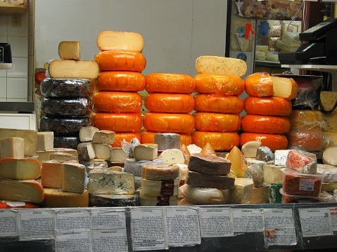 Cheese heads on market counter on market counter, different types and flavors. Gastronomic dainty products, real scene, food market