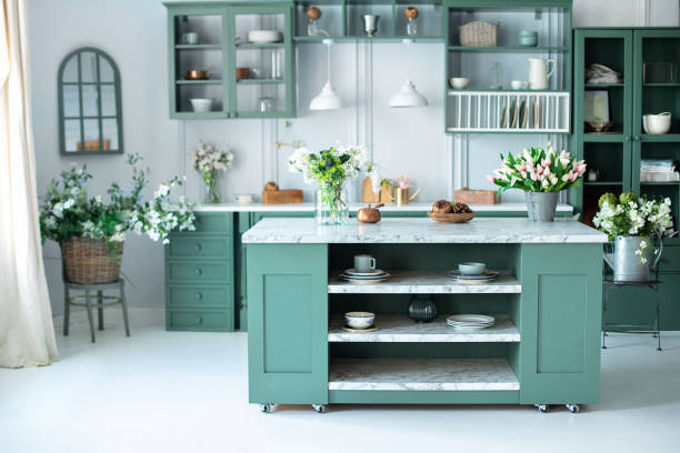 istock Cozy home decor. Kitchen utensils, dishes and plate on table. kitchen island in dining room. Green kitchen interior with furniture. Stylish cuisine with flowers in vase. Wooden kitchen in summer decor 1393795136