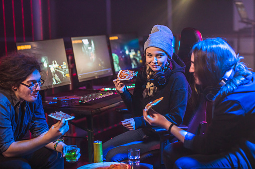 Friends eating pizza while taking a break from playing video games