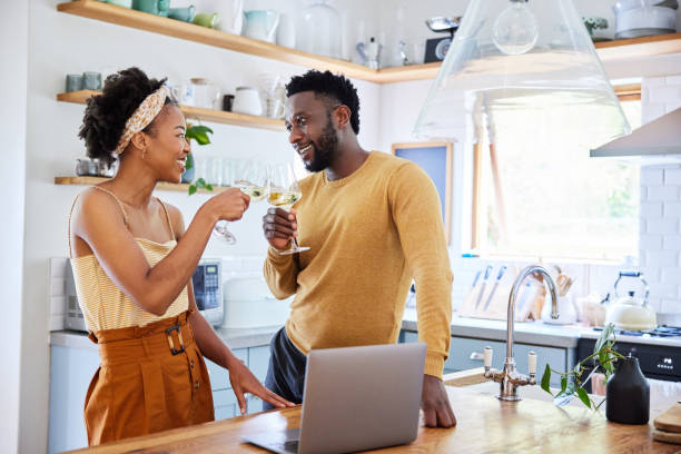 istock Couple drinking wine and using a laptop in their kitchen 1393800470