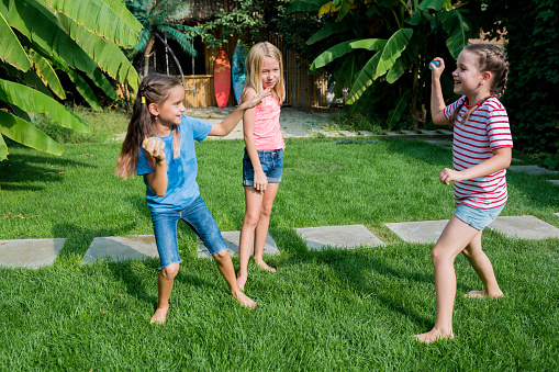 Fun baqckyard water balloons games for kids. Happy girls toss the water balloon from one person to the other. Water Balloon Fight on hot summer day