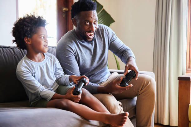 istock Little boy looking at his dad while playing video games at home 1393810018