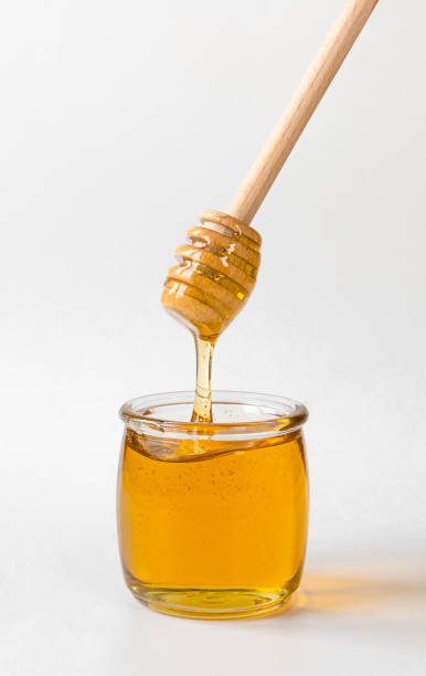 istock Honey pot and dripping honey with wooden spoon 1393810181