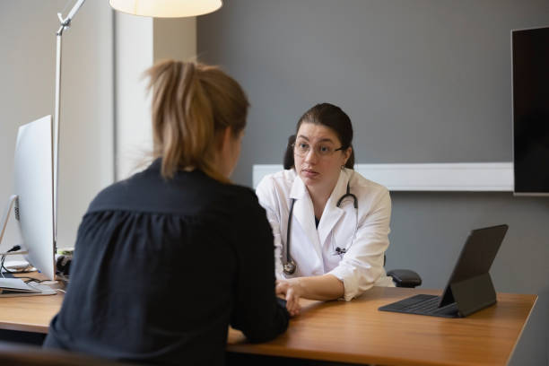 General practitioner consoling a woman patient in clinic Female doctor holding woman patient's hands and comforting her in clinic. General practitioner consoling a woman patient in hospital. mental health stock pictures, royalty-free photos & images