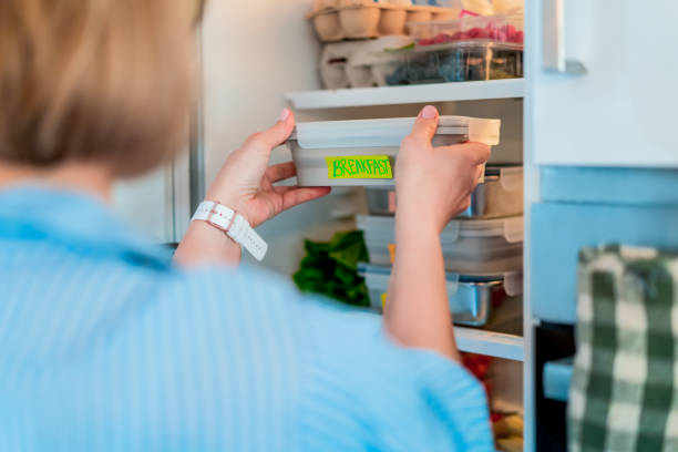 Healthy diet plan for weight loss, daily ready meal menu. Woman taking, putting breakfast box cooked in advance, ready to be served into fridge. Containers with eco healthy food. Pre-cooking concept plan de dieta saludable para bajar de peso, menú diario de comidas preparadas. mujer tomando o poniendo la caja de desayuno cocinada con anticipación, lista para ser servida en la nevera. envases con alimentos eco saludables. concepto de precocción