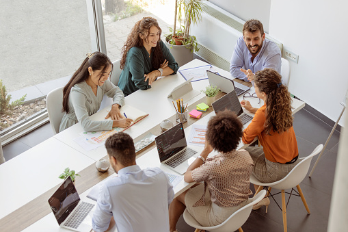 Diverse business people discussing together while having a meeting around a table in a modern office