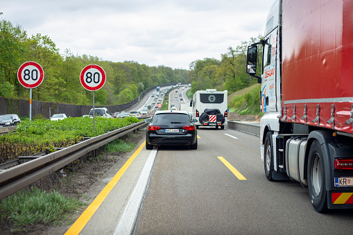 Niedernhausen, Germany - April 23, 2022: Dense traffic in a road works zone on german Autobahn A3 nearby Niedernhausen in Hesse. The Bundesautobahn 3 (abbreviated as BAB 3 or A 3) is a heavily frequented German highway that connects Passau in the Southeast with the Dutch border in Germany. Some road users in the background.