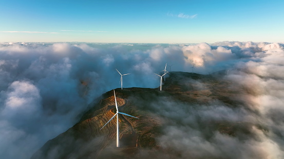 Green alternative wind energy. Renewable energy landscape. Wind turbines produce electricity in the mountains. Wind turbines hidden in the morning fog. Madeira, Portugal. Drone video at dawn. Foggy mystic landscape.