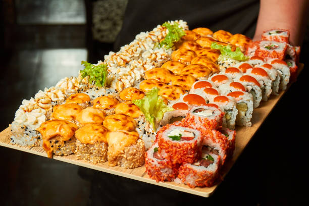 big set of sushi rolls on a board in the hands of a waiter - sushischotel stockfoto's en -beelden