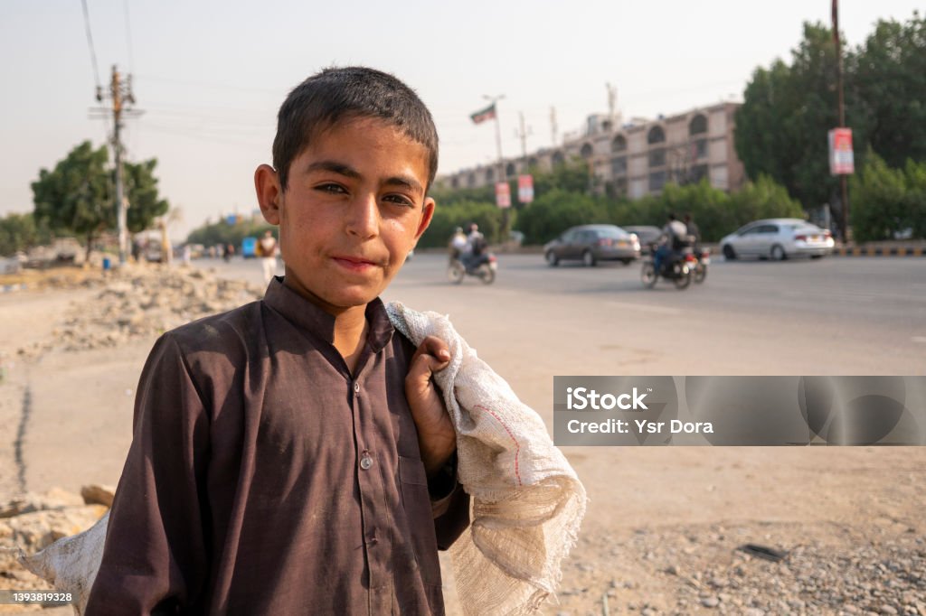 A young Afghan boy from Afghanistan works as a garbage collector in the street of Karachi Pakistan. Karachi, Sindh, Pakistan: In the month of Ramadan, a young Afghani boy from Afghanistan works as a garbage collector in Karachi's streets to be able to feed his family Afghan Ethnicity Stock Photo