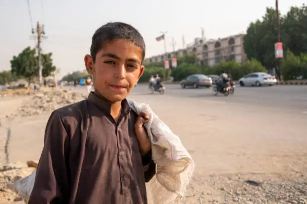 Photo of A young Afghan boy from Afghanistan works as a garbage collector in the street of Karachi Pakistan.