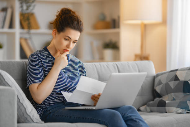istock Woman, sitting on the sofa with a paper receipt 1393819921