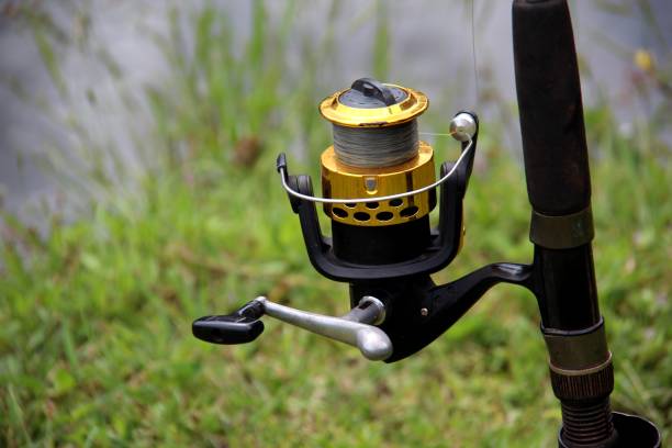 Fishing rod at the bottom of the river. Spool with thread, reel in the foreground. Selective focus.