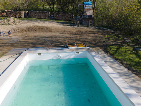 A backyard swimming pool has turned green with algea and dirt and is in need of chlorine treatment. Green water in dirty swimming pool, salt treatment water system is not working , defect and error technology concept.