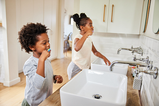 Cute little African brother and sister brushing their teeth in their bathroom at home in the morning