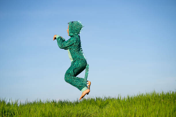 istock A boy in a dinosaur costume is jumping happy in the sky 1393823710