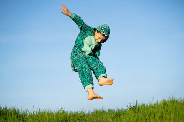 istock A boy in a dinosaur costume is jumping happy in the sky 1393823721