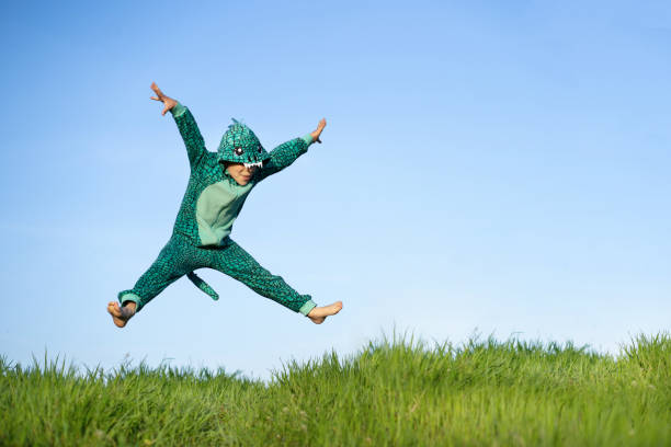 A boy in a dinosaur costume is jumping