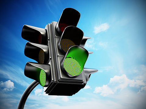 Green traffic light against blue sky.
