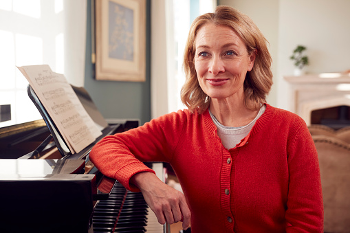 Portrait Of Mature Woman At Home Enjoying Learning To Play Piano