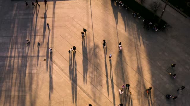 Drone view of people walking in a city park in the evening