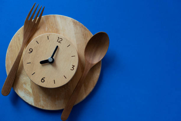 istock Food clock spoon and fork, Healthy food breakfast concept on blue table background 1393830496