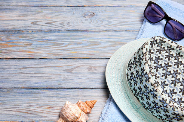 istock Hat, towel, sunglasses and Exotic sea shells on blue wooden background with copy space 1393834949