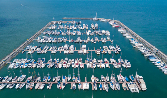Marine port for yacht, motorboat, sailboat parking service and moorings for luxury and wealthy millionaire in aerial view with many ships anchoring alongside the dock bay
