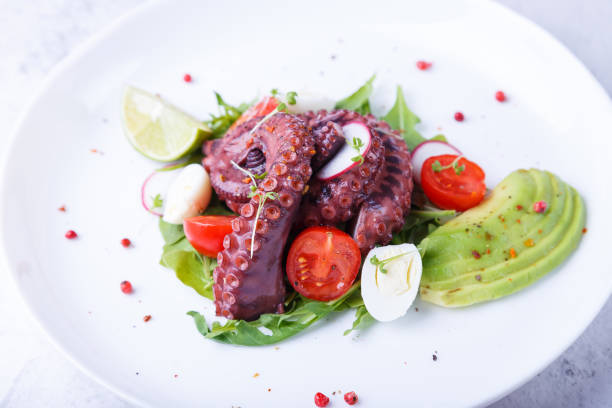 istock Warm salad with octopus, cherry tomatoes, avocado, arugula, quail eggs, radishes and lime on a white plate. Traditional Middle 1393837362