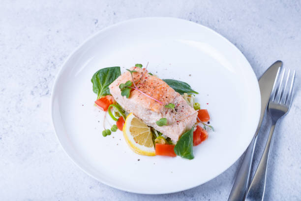 istock Trout (salmon) with vegetables, lemon and microgreens, cooked by the confit method. A traditional French dish. Close-up, selective photo 1393837408